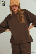 Woman wearing a brown outfit with a matching cap on a plain background