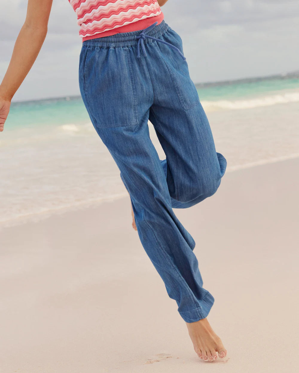 Person wearing blue denim pants on a beach