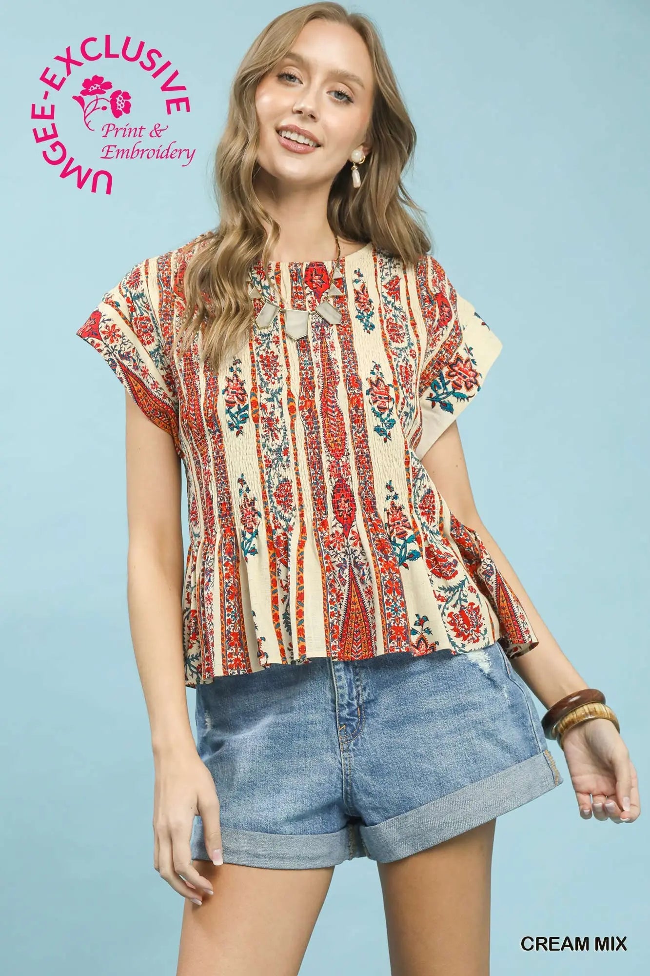 Woman wearing a floral blouse and denim shorts on a light blue background