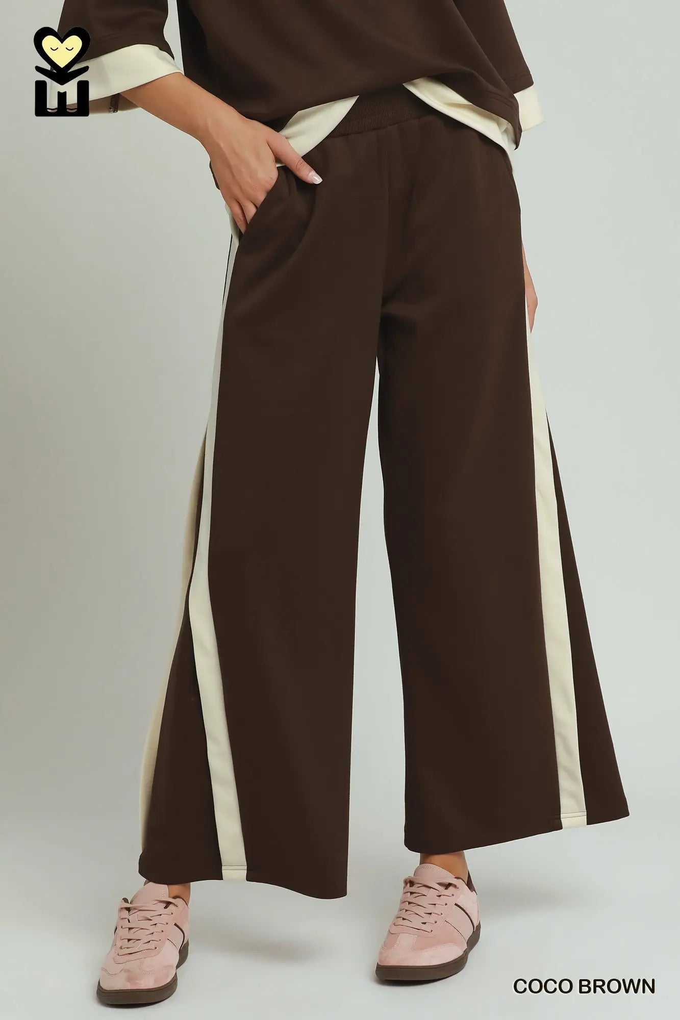 Brown wide-leg pants with white stripes worn by a person on a light gray background