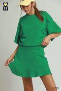 Woman wearing a green dress and yellow cap on a plain background