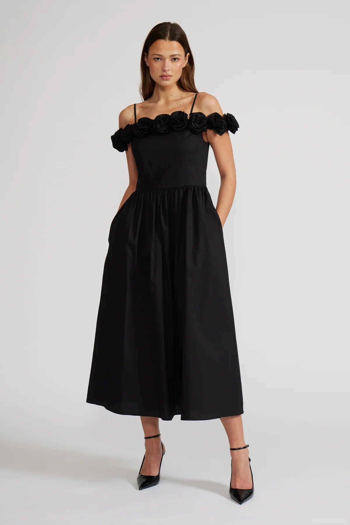 Woman wearing a black dress with ruffled shoulders on a white background