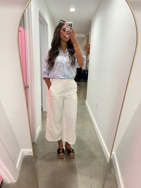 Person wearing a white outfit standing in front of a mirror.