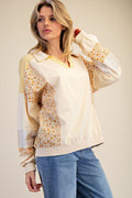 Woman wearing a cream blouse with floral sleeves and blue jeans on a beige background
