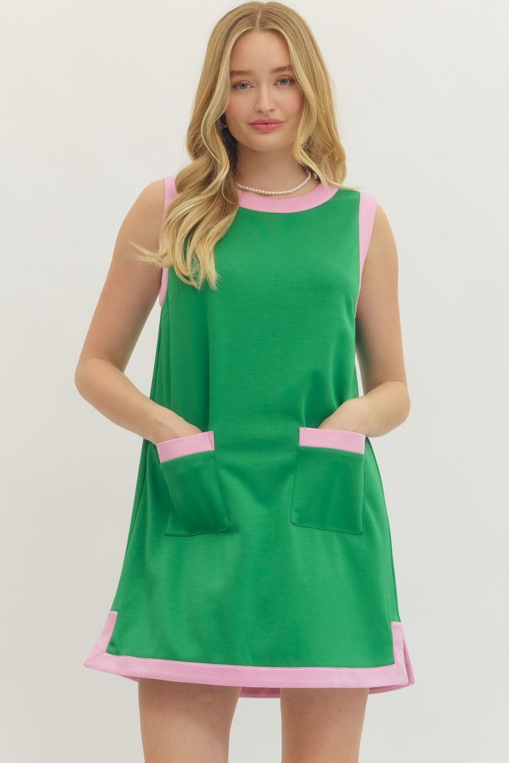 Green dress with pink accents worn by a model on a white background