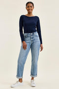 Woman wearing a navy long-sleeve top and light blue jeans on a beige background