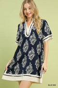 Woman wearing a navy blue dress with white floral patterns on a light green background