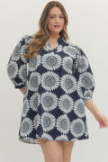Woman wearing a navy dress with white floral pattern on a plain background