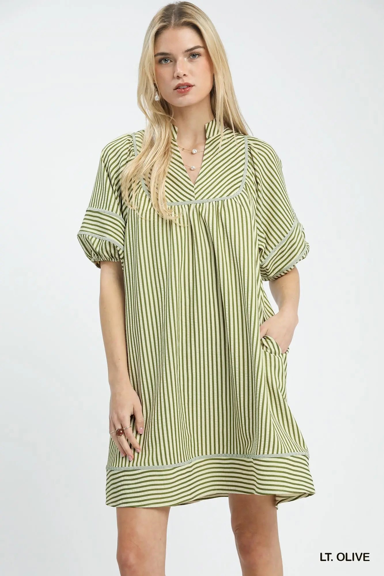 Woman wearing a light olive striped dress on a white background