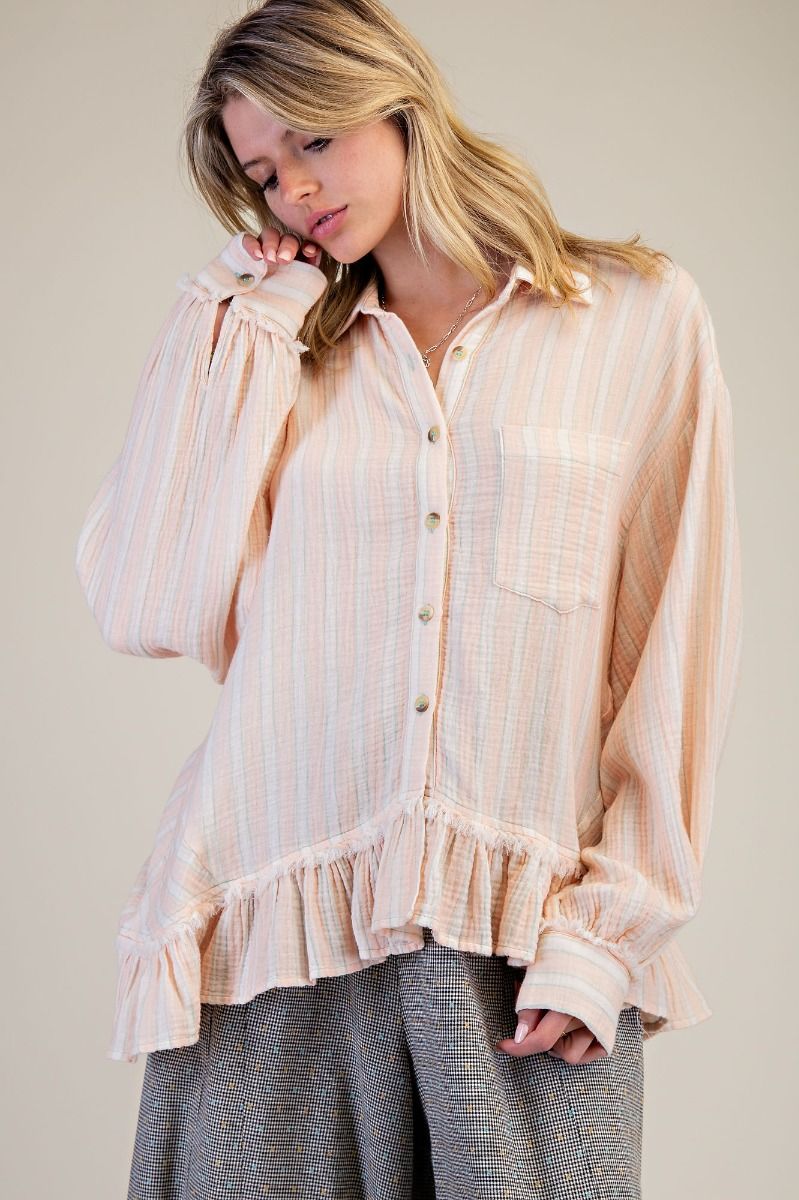 Woman wearing a light pink blouse with ruffled details on a plain background
