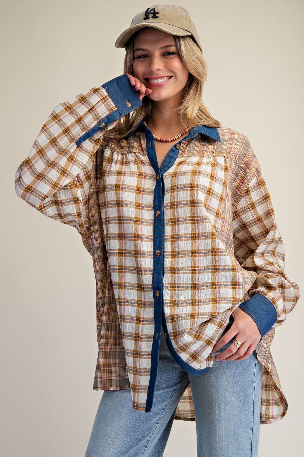 Woman wearing a plaid shirt with blue accents and jeans against a beige background