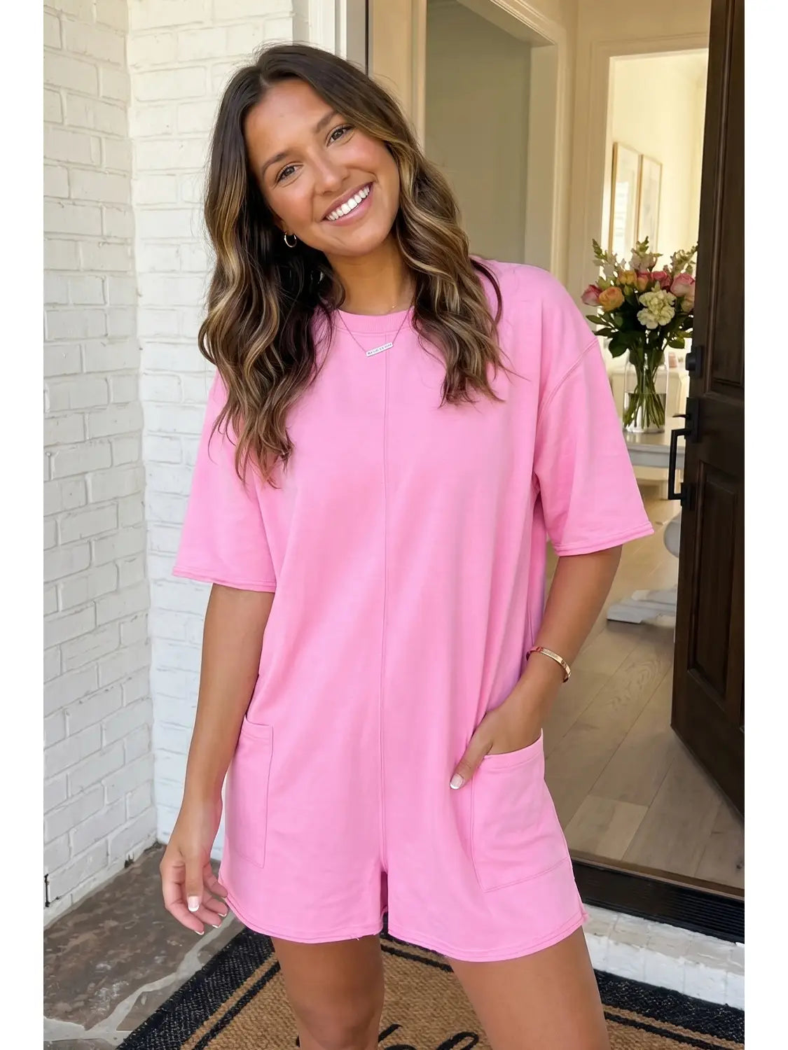 Woman wearing a pink outfit standing in a doorway.