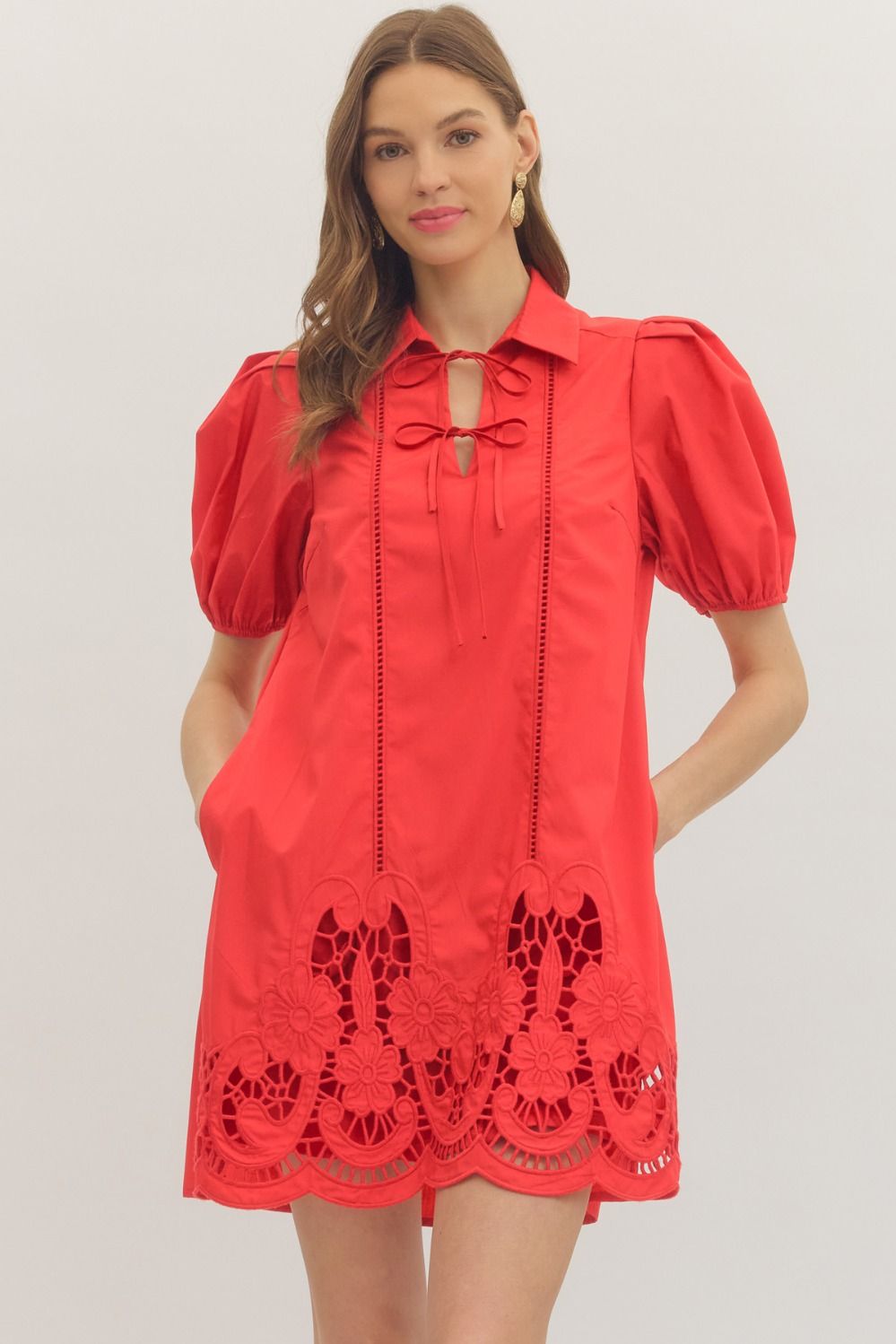 Woman wearing a red dress with lace details on a plain background