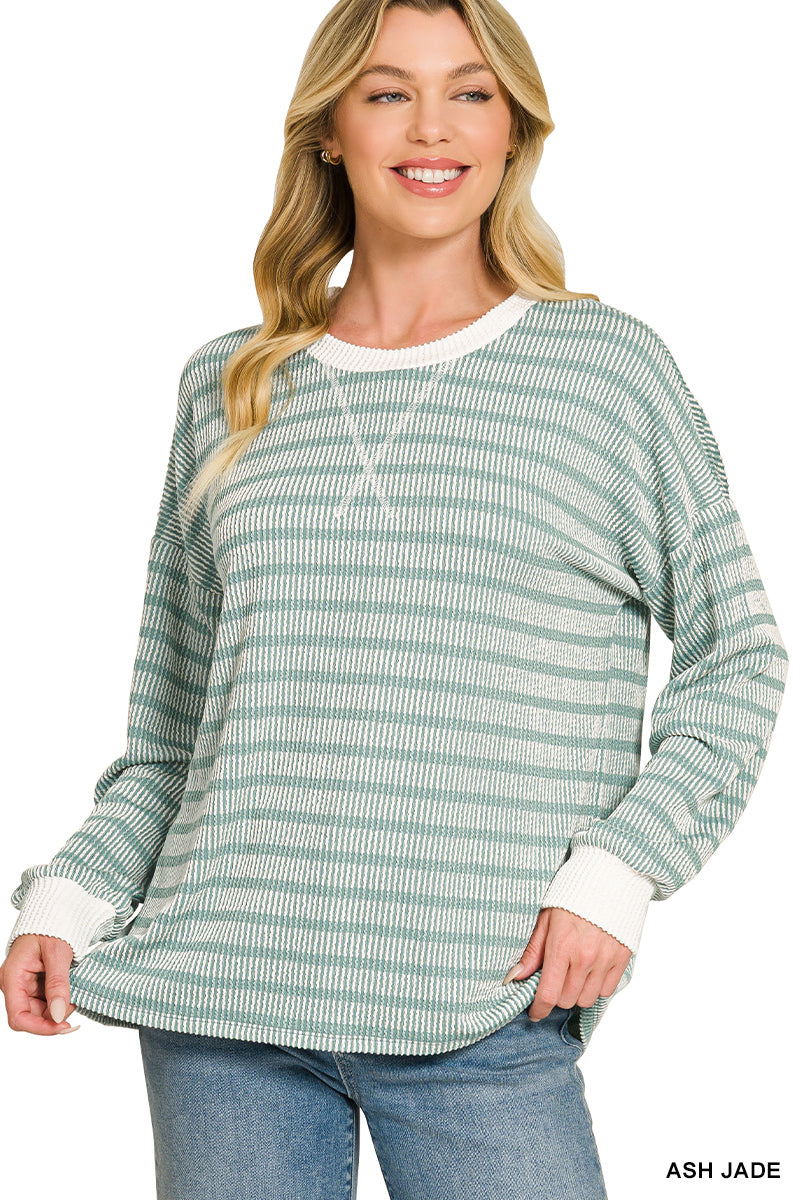 A woman wearing a light green and white striped long-sleeve knit top with white ribbed trim at the crew neck, cuffs, and hem, paired with blue jeans. The text 'ASH JADE' is visible in the bottom right corner.