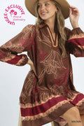 A woman wearing a brown long-sleeve dress with a beige floral pattern and red border details, styled with a tan hat against a light gray studio background. A pink 'UNIQUELY EXCLUSIVE Print & Embroidery' logo is visible in the top left, and the word 'BROWN' appears in the bottom right.