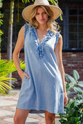 Woman wearing a light blue dress with lace details and a wide-brimmed hat outdoors.
