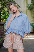 Woman wearing a denim shirt and striped shorts outdoors