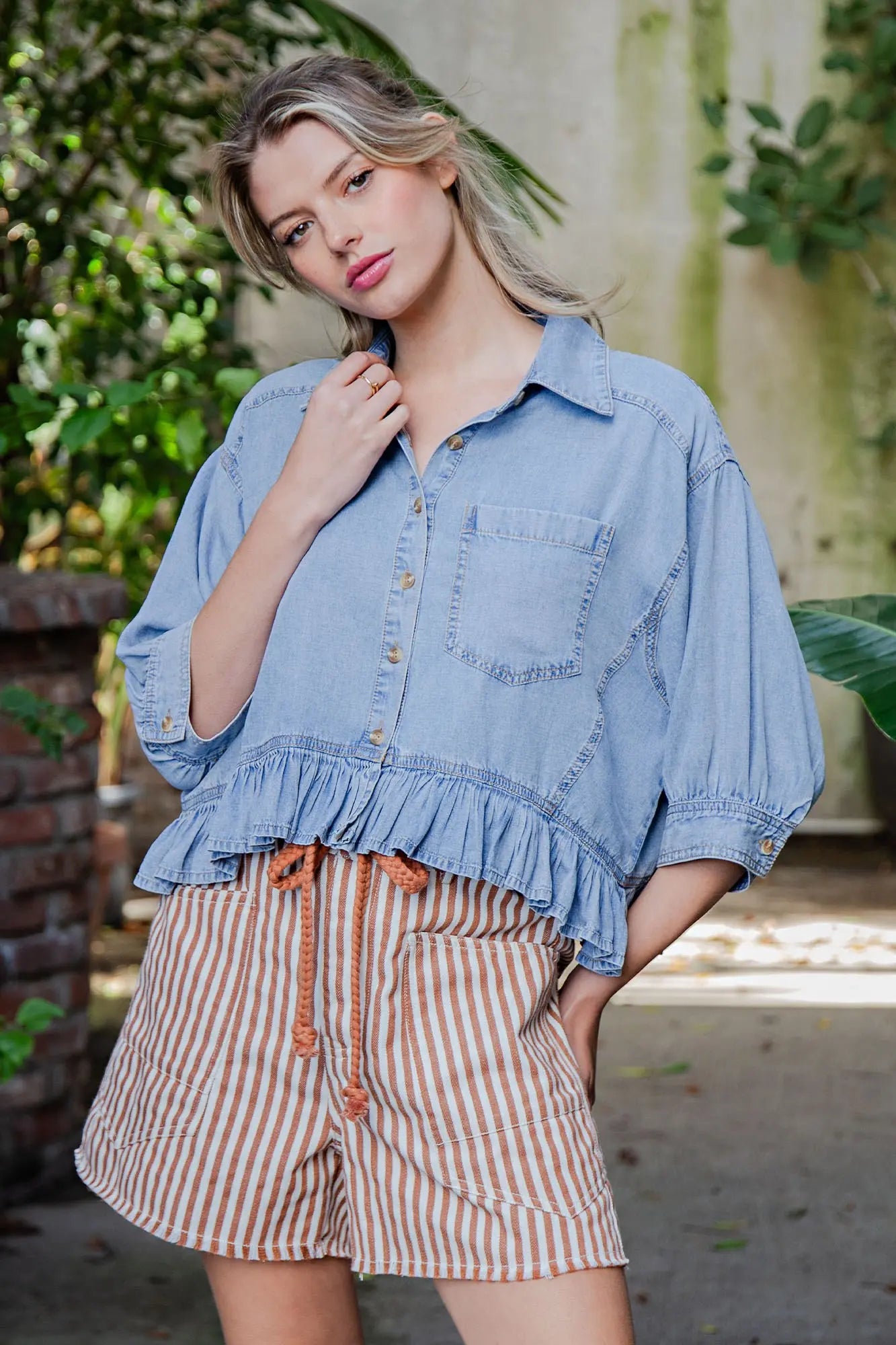 Woman wearing a denim shirt and striped shorts outdoors