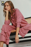 Woman wearing a mauve dress sitting on a striped bench.