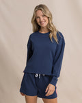 Woman wearing a navy blue sweatshirt and shorts set on a beige background