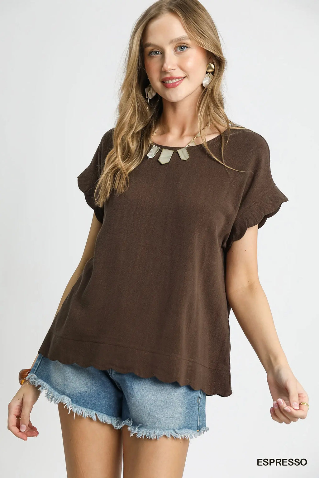 Woman wearing a brown top and denim shorts on a white background