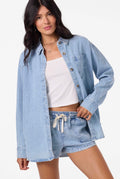Woman wearing a light blue denim jacket and shorts on a white background