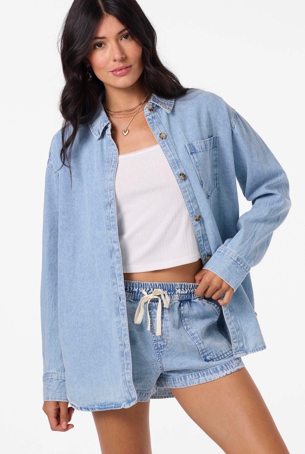 Woman wearing a light blue denim jacket and shorts on a white background