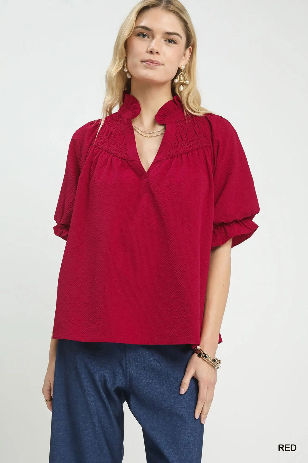 Woman wearing a red blouse with ruffled collar on a white background