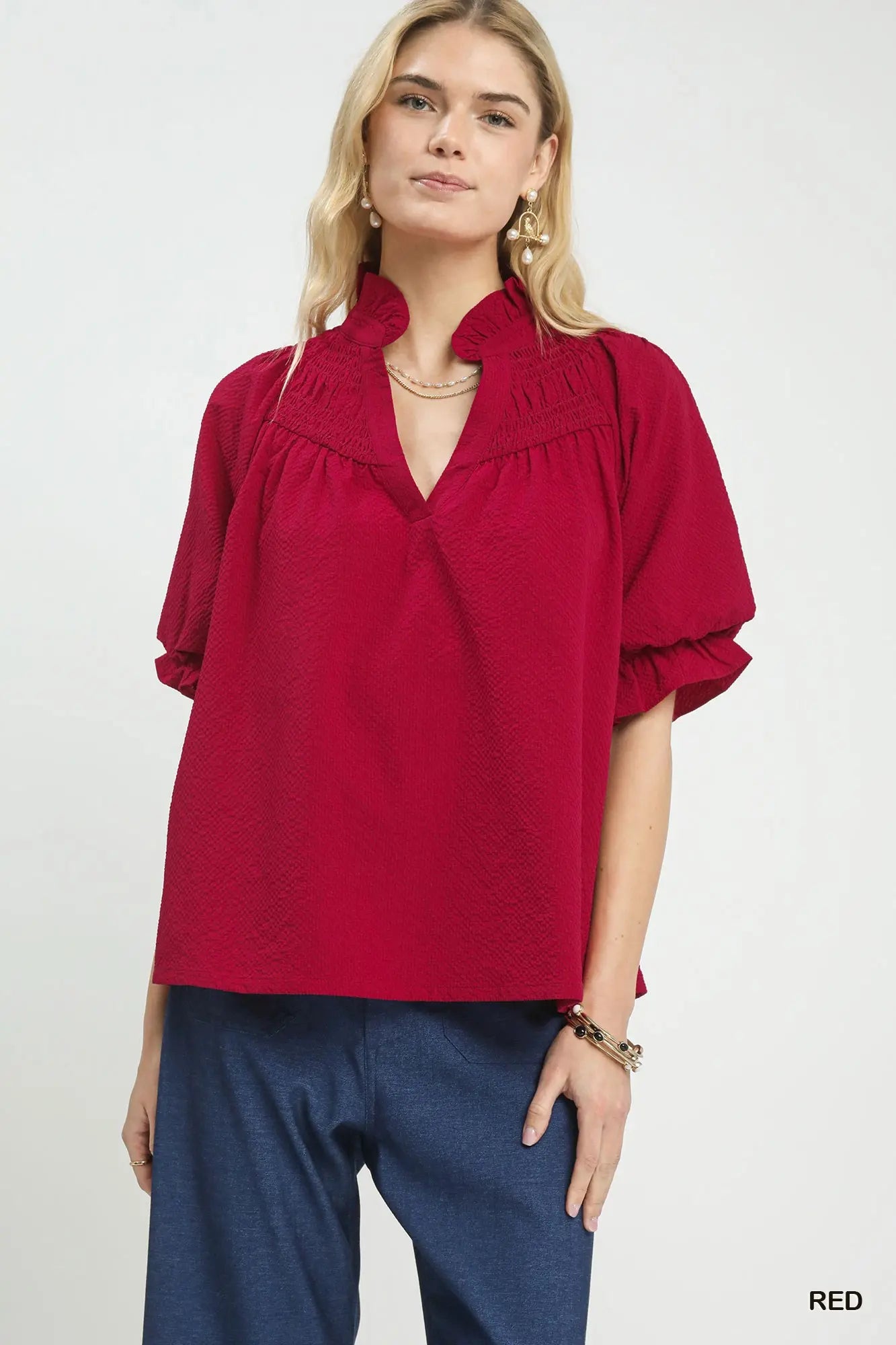 Woman wearing a red blouse with ruffled collar on a white background