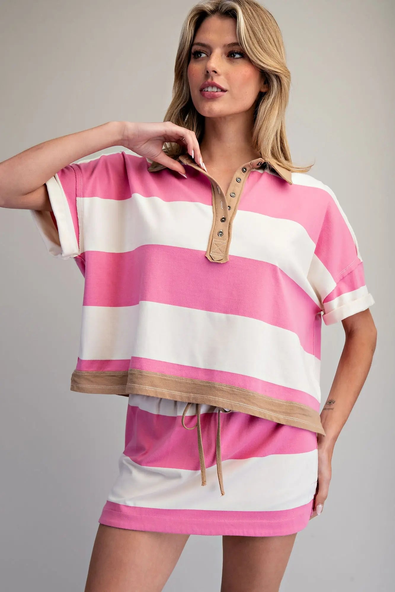 Woman wearing a pink and white striped dress with a brown waistband on a gray background