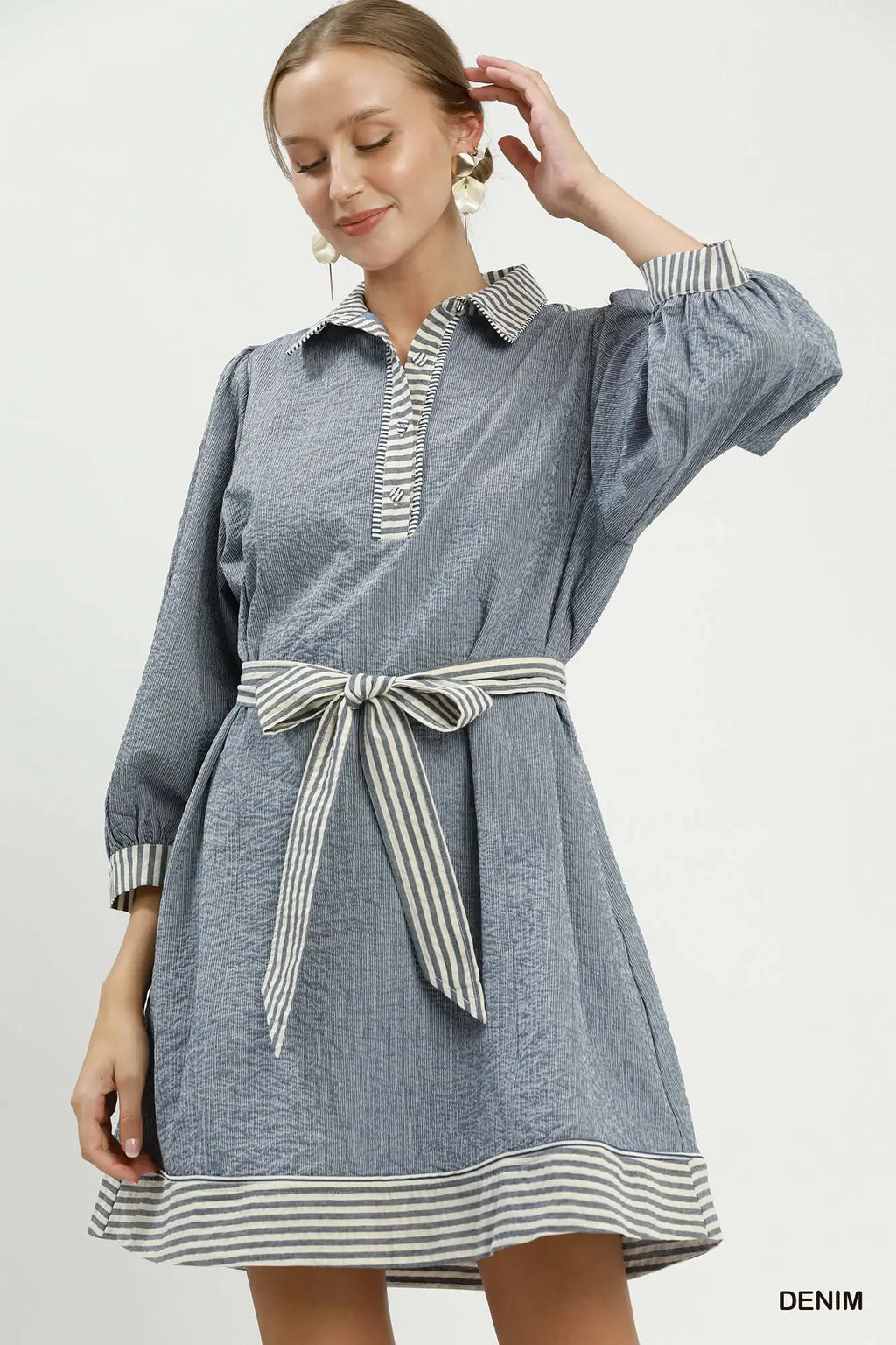 Woman wearing a denim dress with striped details on a white background