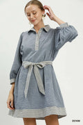 Woman wearing a denim dress with striped details on a white background