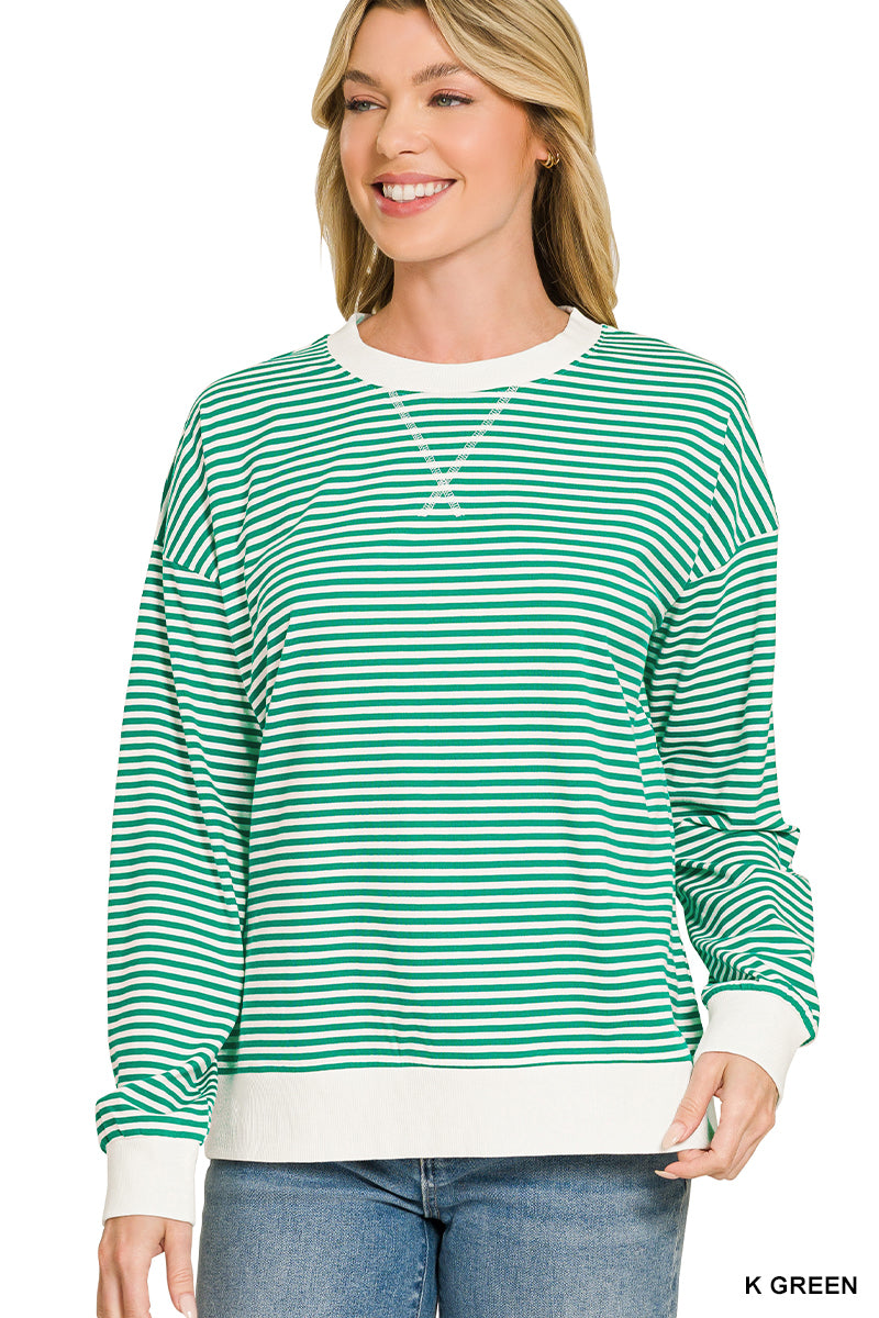 A woman wearing a green and white horizontally striped long-sleeve crewneck sweatshirt with white ribbed trim, paired with blue jeans, against a plain white background.