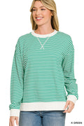 A woman wearing a green and white horizontally striped long-sleeve crewneck sweatshirt with white ribbed trim, paired with blue jeans, against a plain white background.