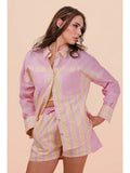 Woman wearing a pink and yellow striped shirt and shorts on a beige background