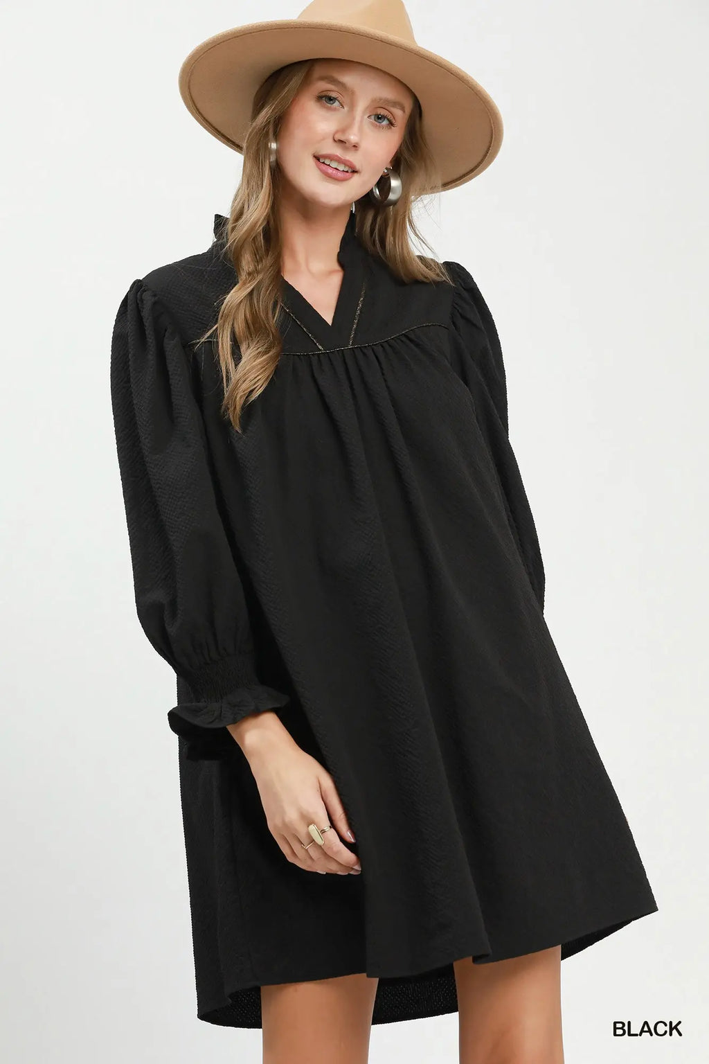 Woman wearing a black dress and beige hat on a white background