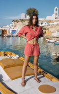Woman in a pink outfit standing on a dock with a scenic background