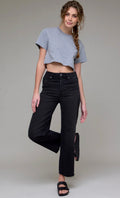 A woman modeling a light gray short-sleeve crop top and black wide-leg jeans against a plain light gray studio background.