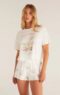 Woman wearing a white graphic t-shirt and shorts set with 'Palm Springs' text on a plain background