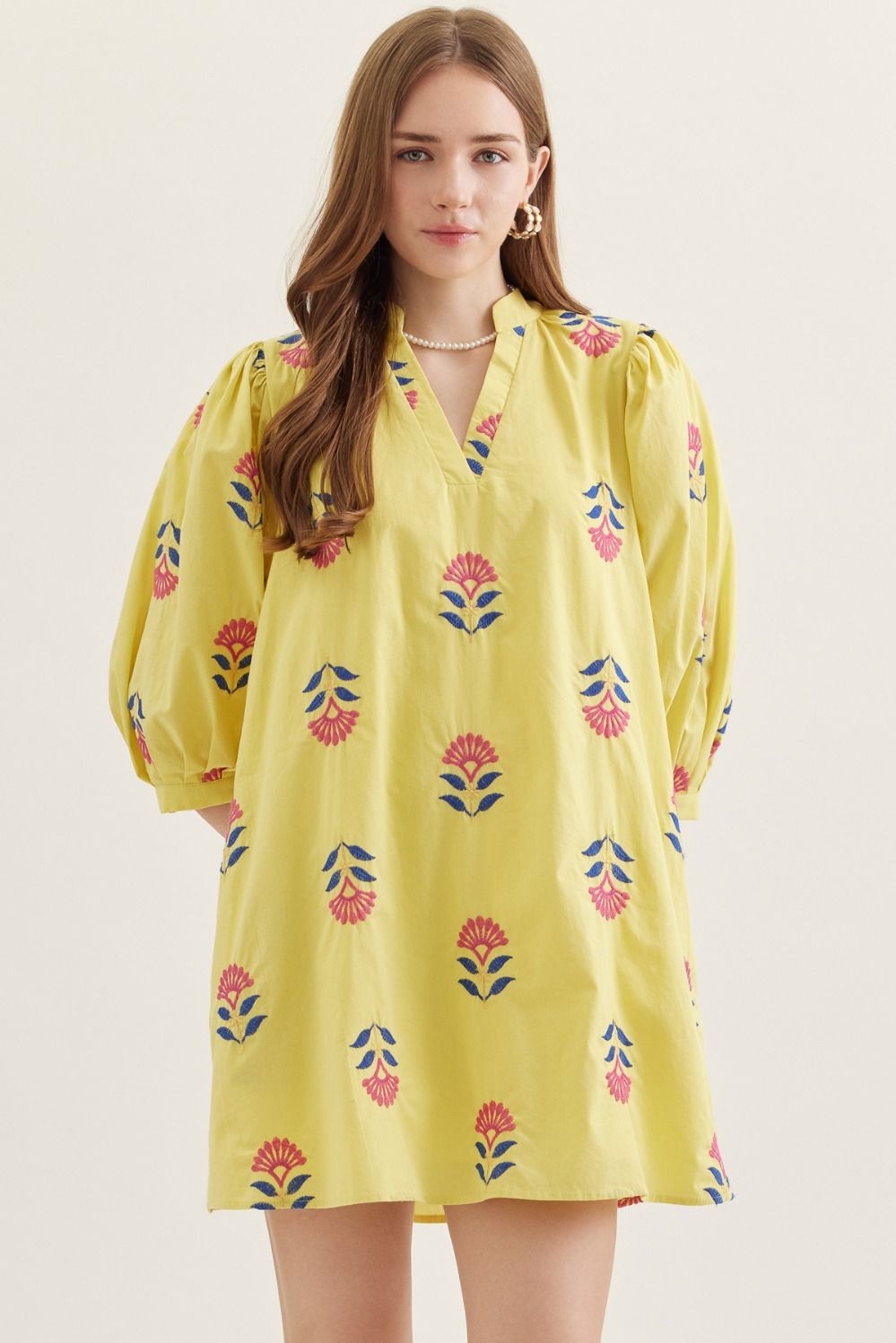 Woman wearing a yellow floral dress against a white background