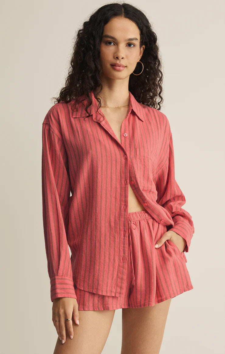 Woman wearing a red striped shirt and shorts set against a beige background