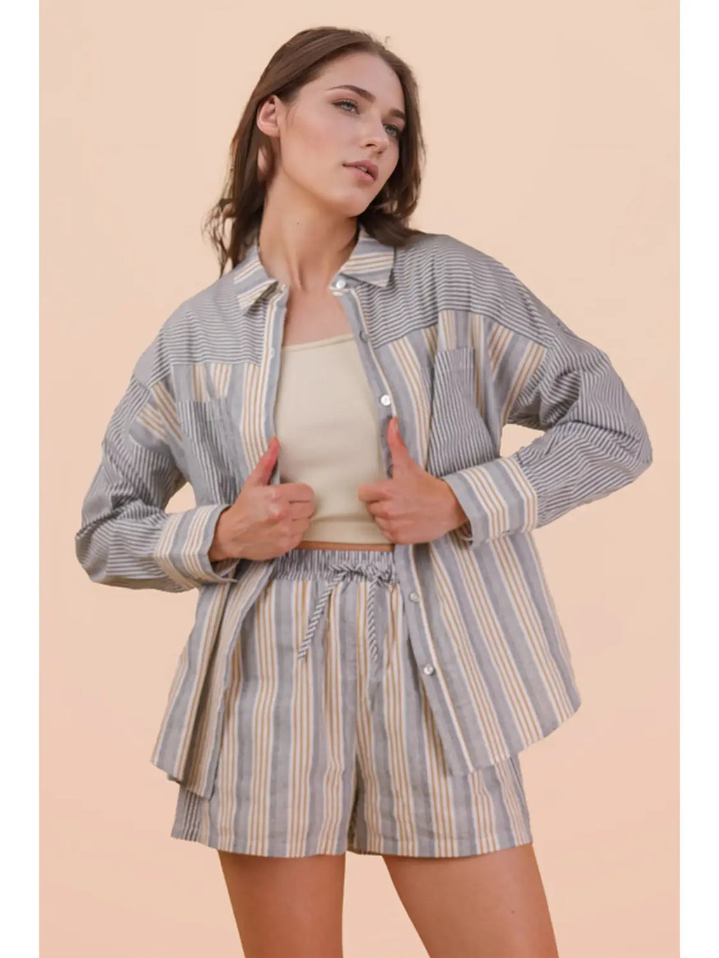 Woman wearing a striped shirt and shorts set against a beige background