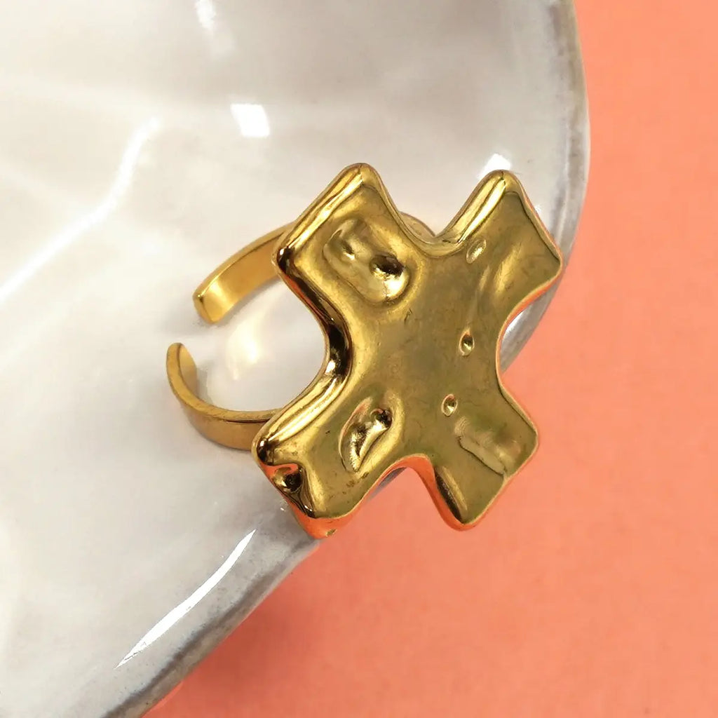 Gold ring with a unique design on a white and orange background