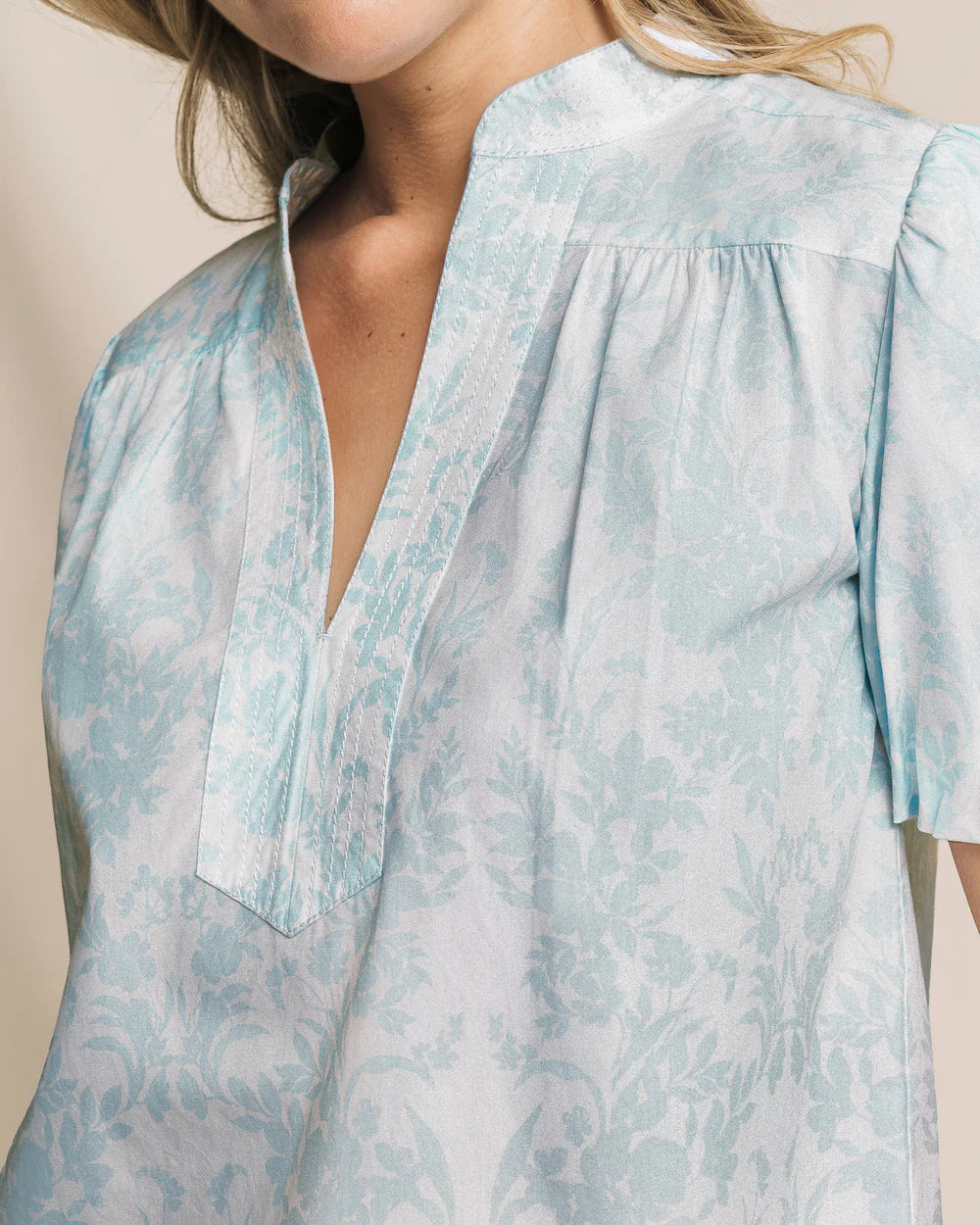 Close-up of a light blue floral blouse worn by a person.