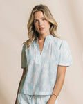 Woman wearing a light blue tie-dye shirt with a beige background