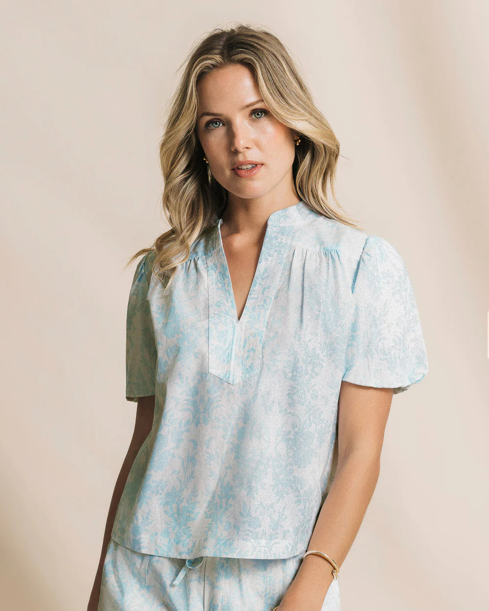 Woman wearing a light blue tie-dye shirt with a beige background