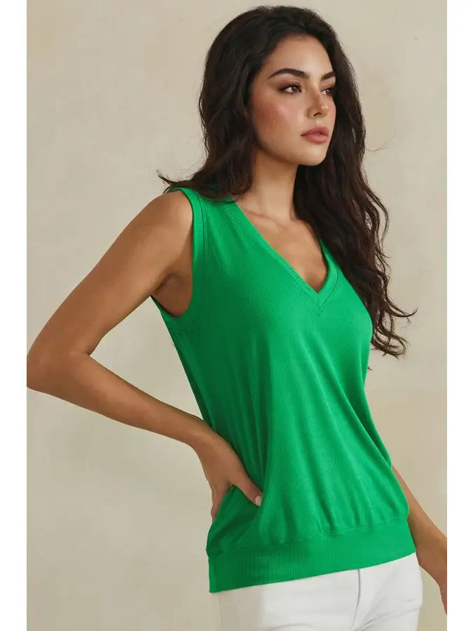 Woman wearing a green sleeveless top against a beige background