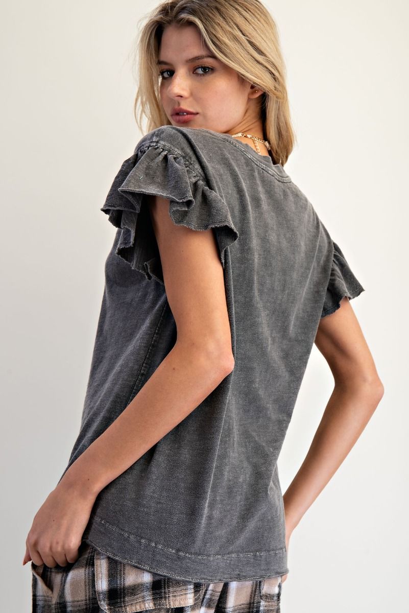 A woman wearing a washed charcoal gray short-sleeve top with ruffled sleeves, shown from a three-quarters back view against a plain light background.