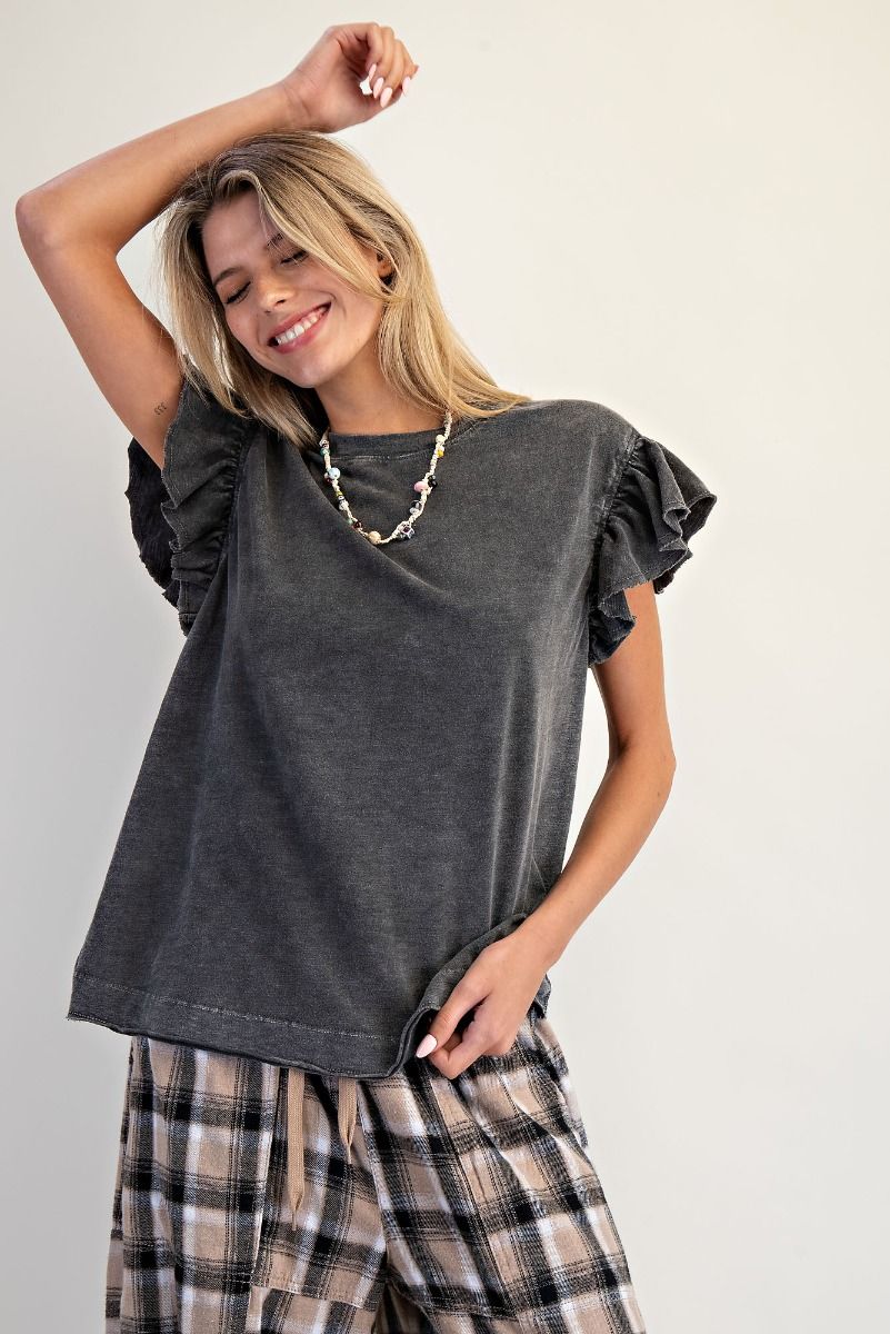 A woman modeling a dark gray short-sleeve top with ruffled sleeves and a relaxed fit, paired with plaid pants, against a plain light background.