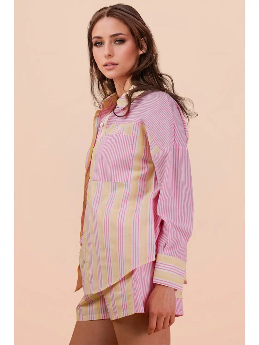 Woman wearing a pink and yellow striped dress against a beige background